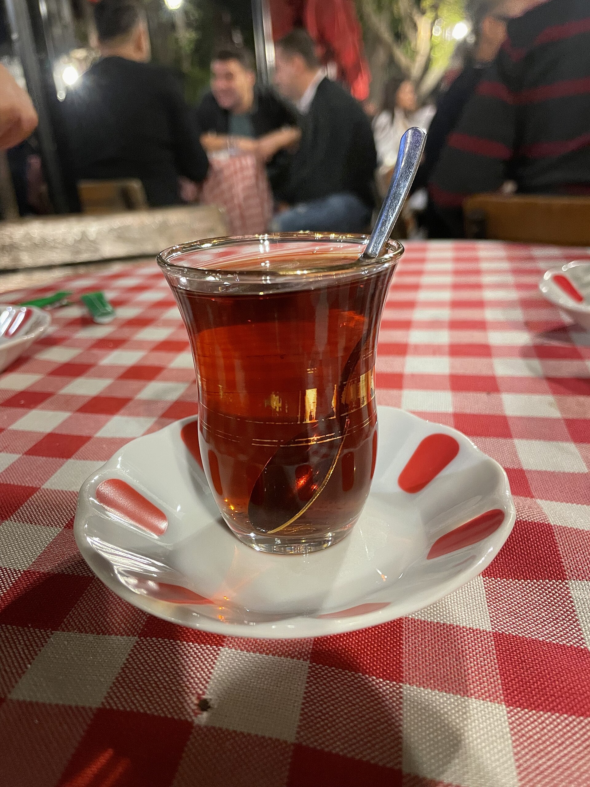 Kareli örtü üstünde, kırmızı benekli tabakta ince belli bir bardak çay